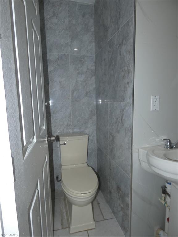 Bathroom featuring tile walls, toilet, and tile patterned flooring