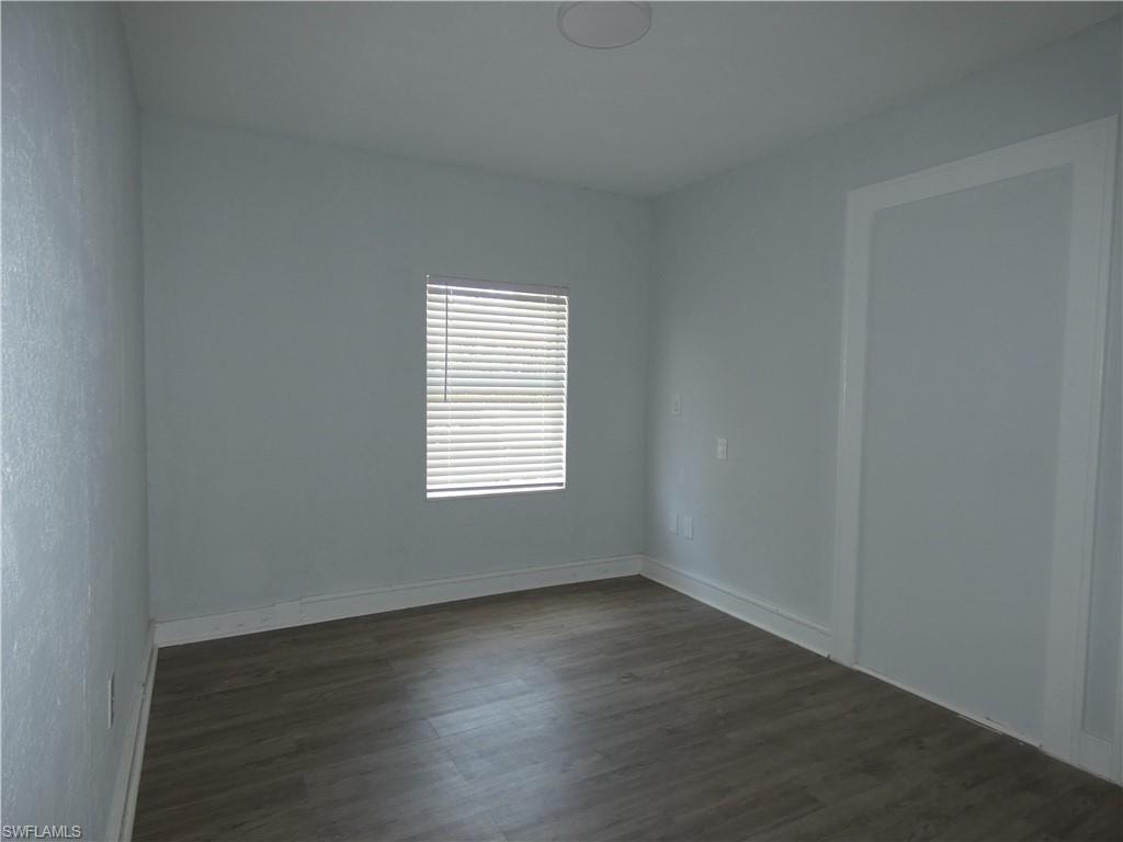 Empty room featuring dark wood-style floors and baseboards