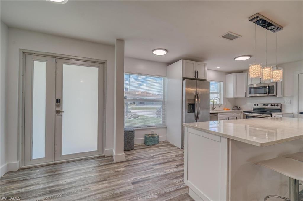 Kitchen featuring stainless steel appliances, light stone countertops, white cabinets, light wood finished floors, and recessed lighting