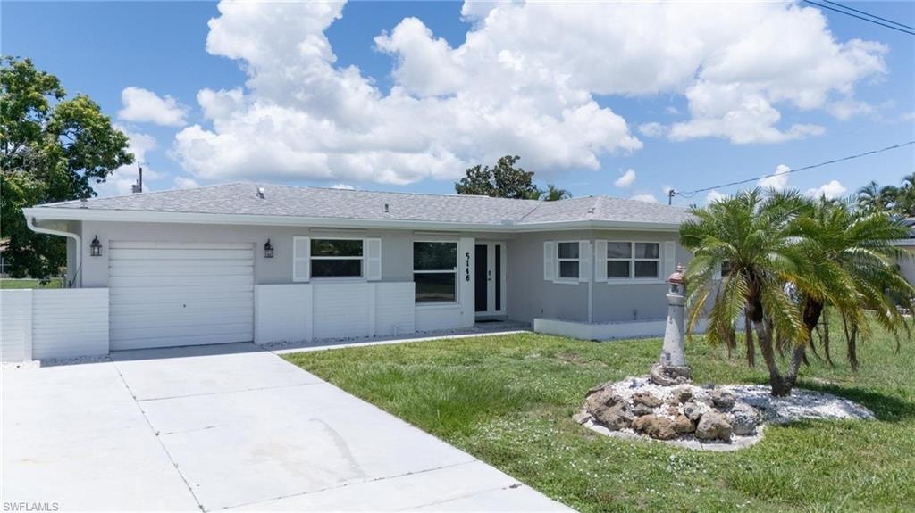 Ranch-style house with concrete driveway, a garage, stucco siding, and a front lawn
