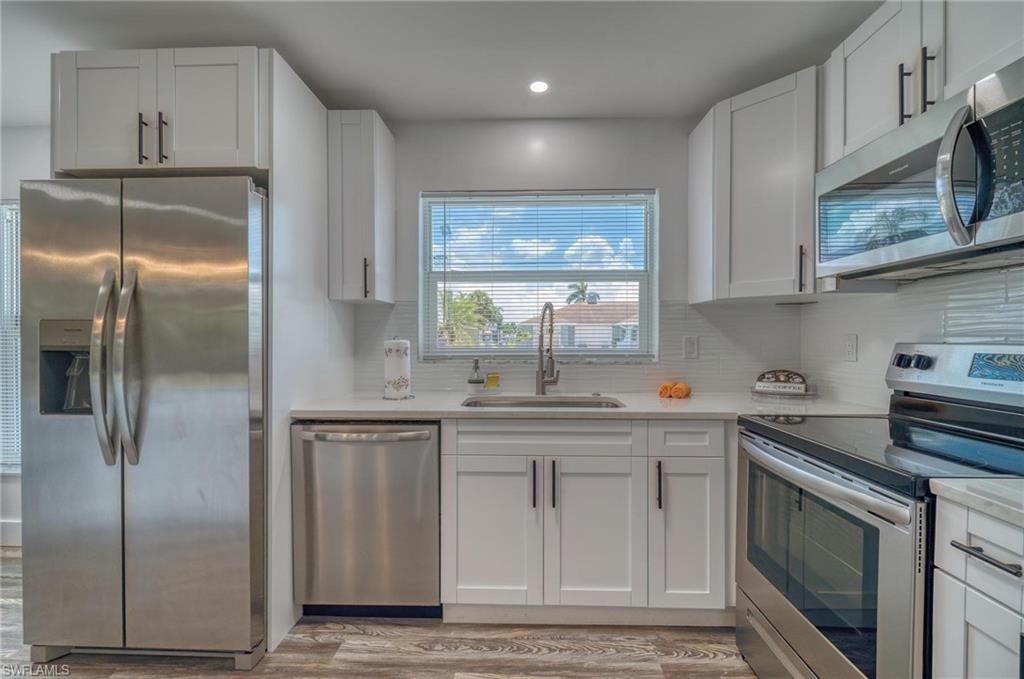 Kitchen with stainless steel appliances, a sink, light countertops, tasteful backsplash, and recessed lighting