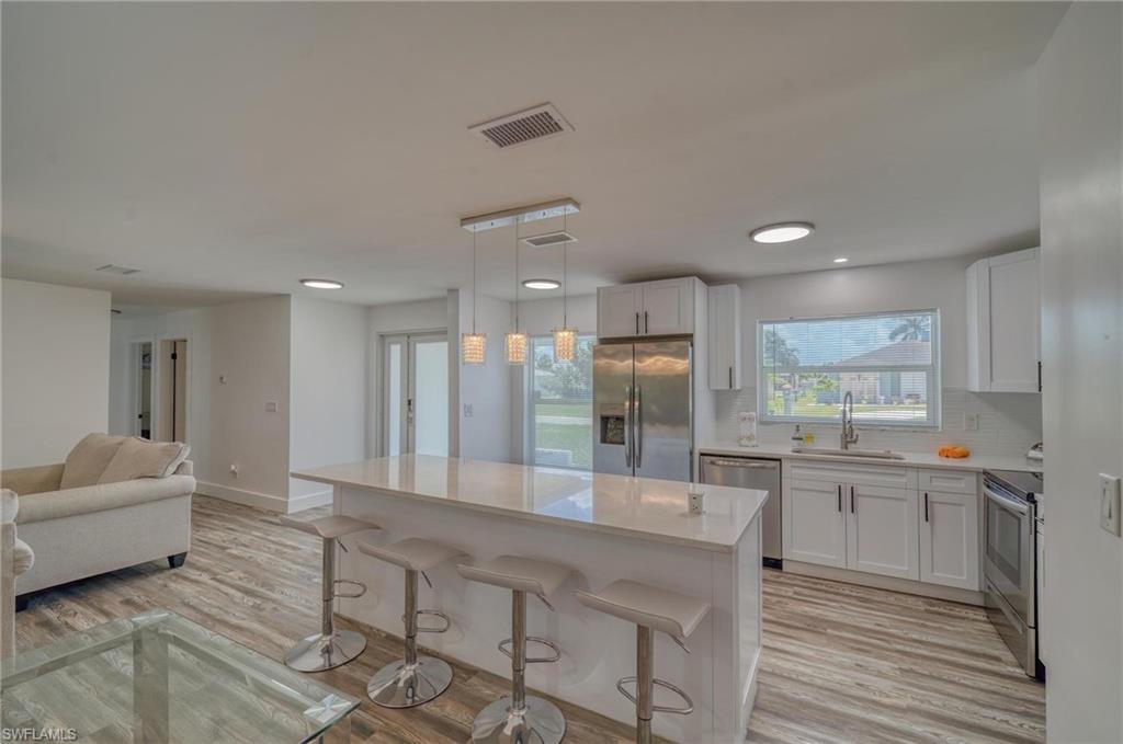 Kitchen featuring appliances with stainless steel finishes, a sink, light countertops, white cabinets, and recessed lighting