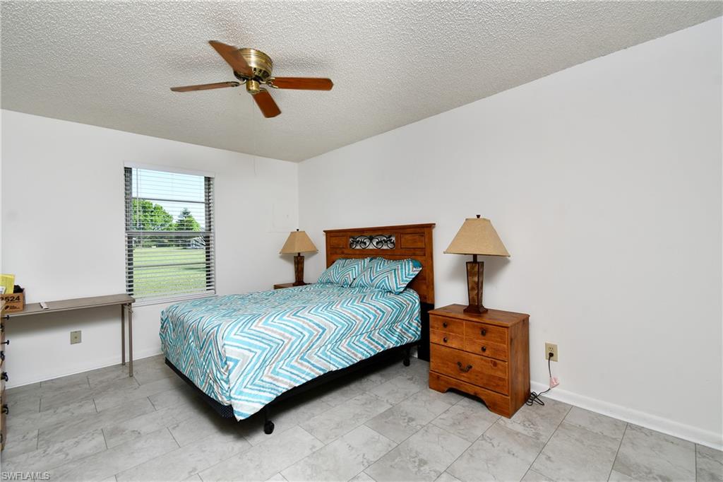 Bedroom featuring a textured ceiling, ceiling fan, and baseboards