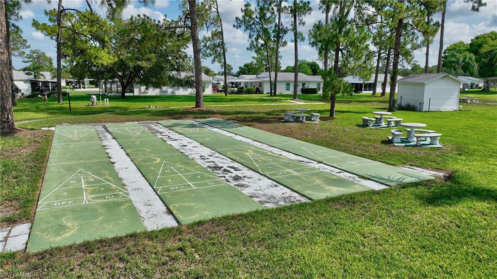 View of home's community featuring a lawn and shuffleboard