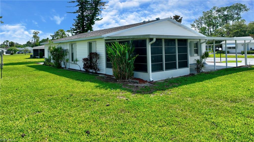 View of side of home with a sunroom, a yard, and an attached carport