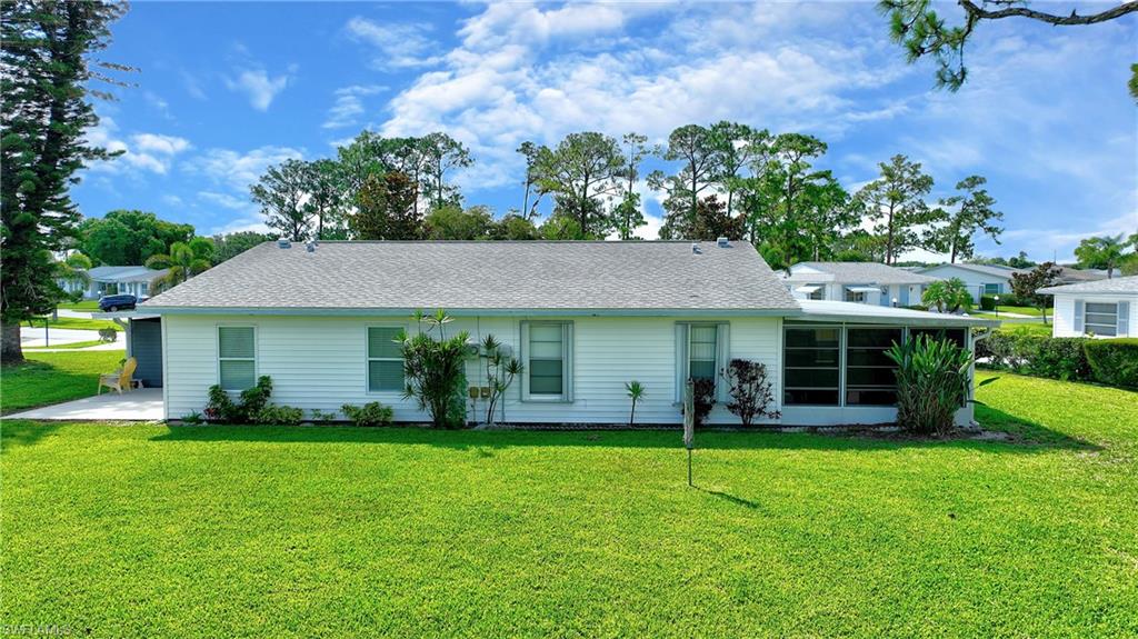 Back of house featuring a lawn, a sunroom, and roof with shingles