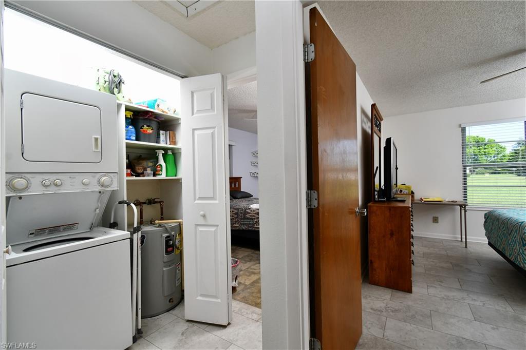 Laundry room with estacked washer and dryer, a textured ceiling, and light tile patterned floors