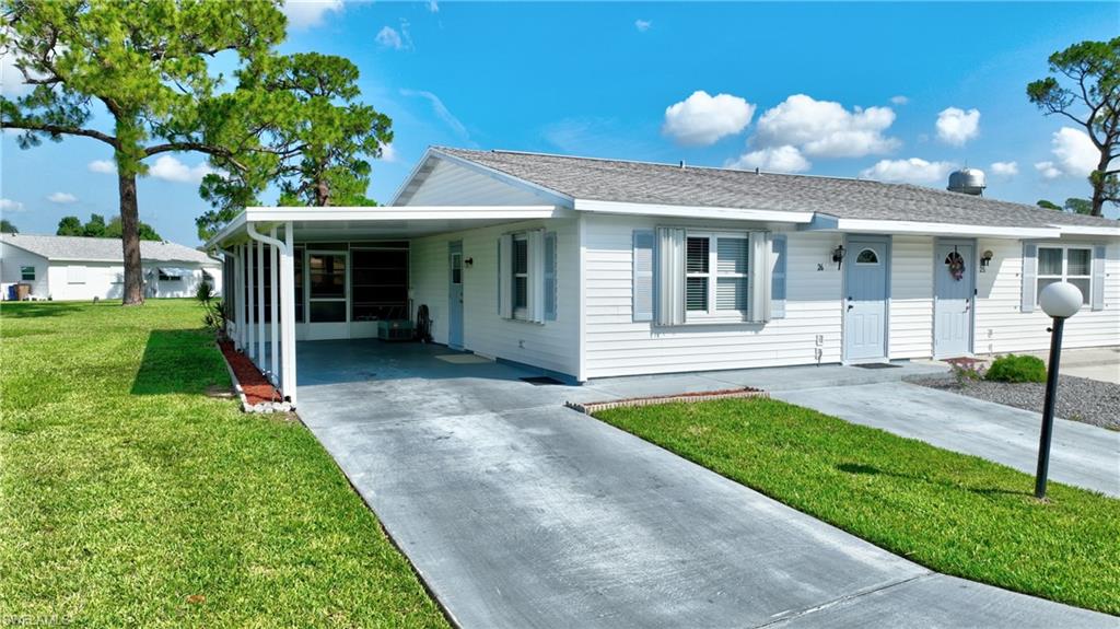 Single story home with driveway, a front yard, and a carport