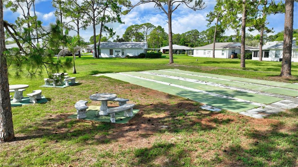 View of property's community featuring a lawn and shuffleboard