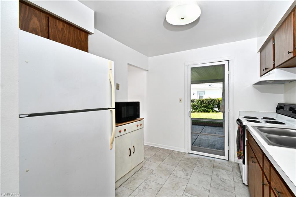 Kitchen featuring freestanding refrigerator, black microwave, range with electric cooktop, under cabinet range hood, and light countertops