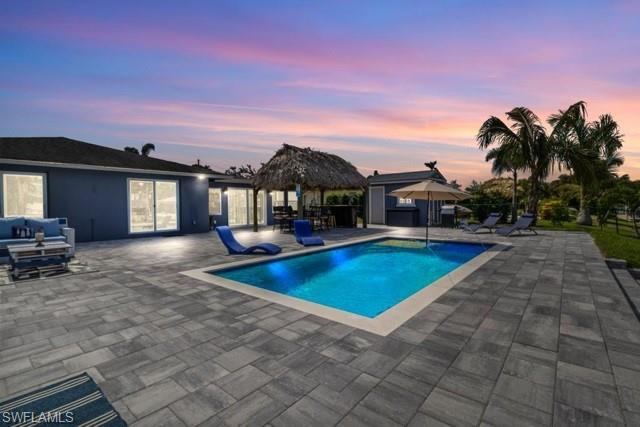 Pool at dusk with a patio area, a gazebo, an outdoor pool, and an outdoor hangout area