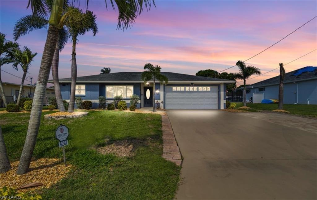 Single story home with a garage, driveway, and a yard