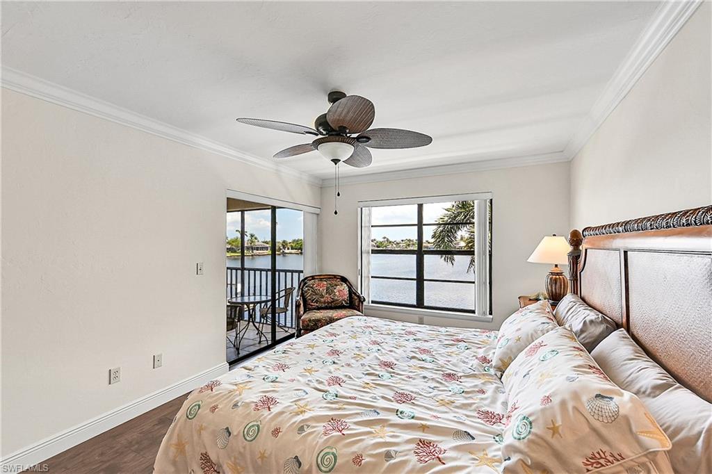 Bedroom featuring access to exterior, wood finished floors, ornamental molding, baseboards, and a water view