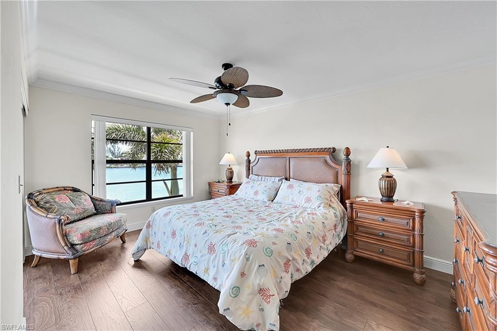 Bedroom with wood finished floors, crown molding, baseboards, and ceiling fan