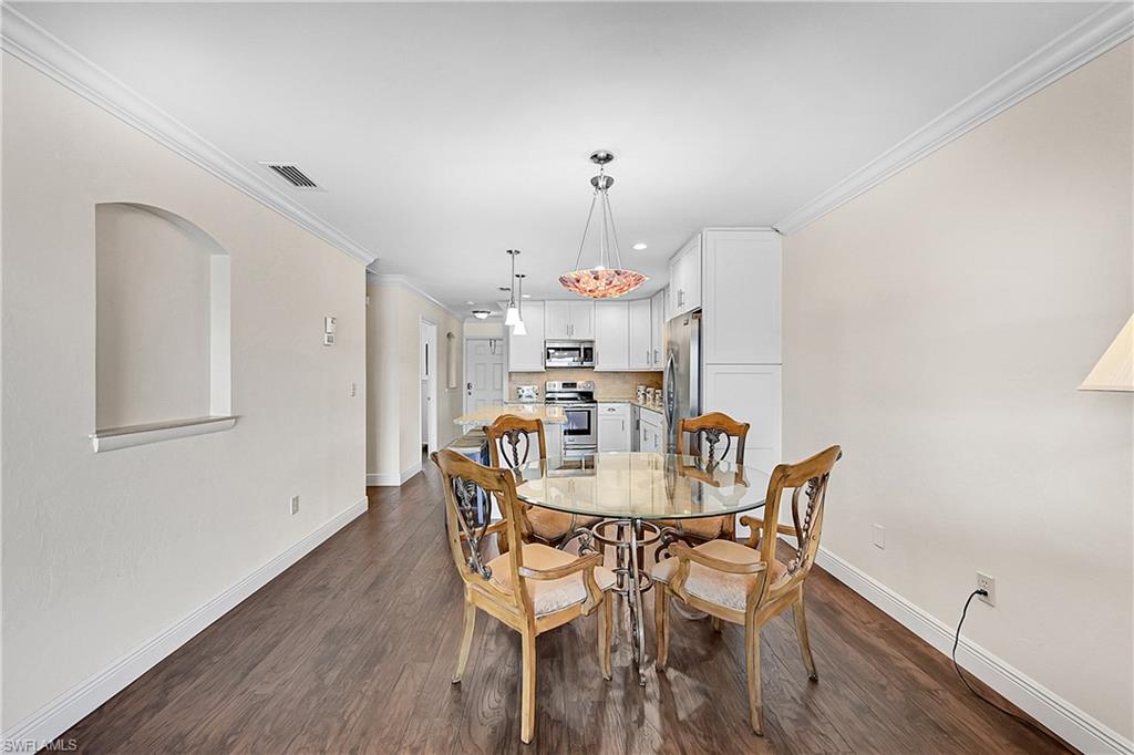 Dining space featuring baseboards, crown molding, dark wood-style flooring, and recessed lighting