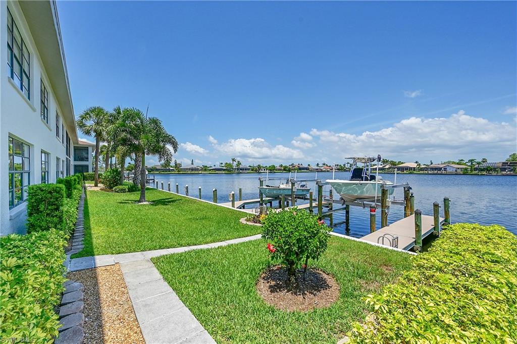 Dock area featuring boat lift, a lawn, and a water view