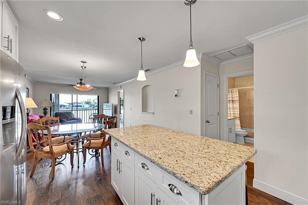 Kitchen with stainless steel fridge, a kitchen island, dark wood finished floors, crown molding, and white cabinets