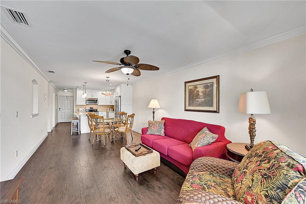 Living area with baseboards, a ceiling fan, crown molding, and dark wood-style floors