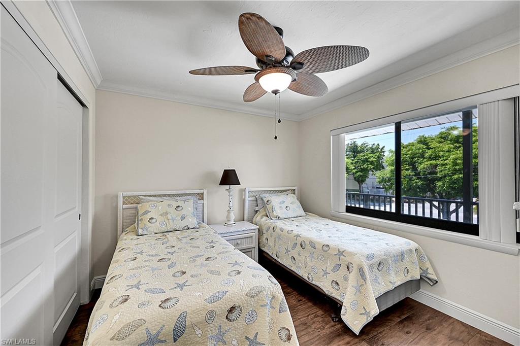 Guest Bedroom with baseboards, crown molding, dark wood finished floors, a closet, and ceiling fan