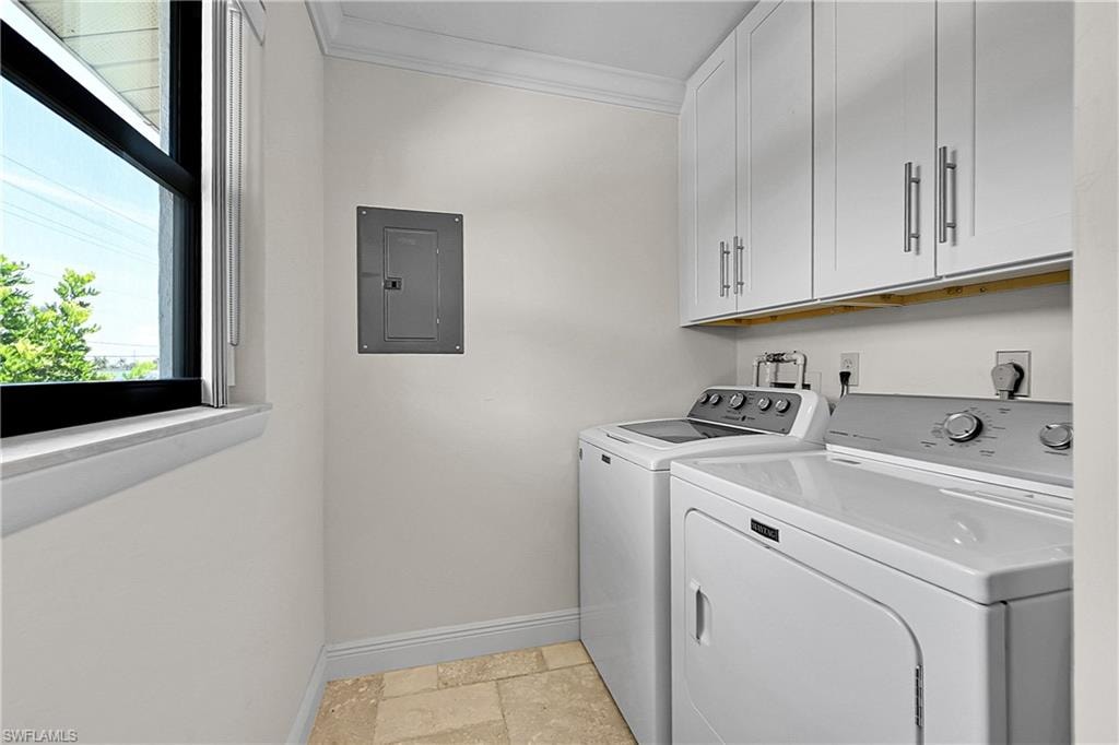 Laundry room with cabinet space, electric panel, baseboards, washing machine and clothes dryer, and crown molding