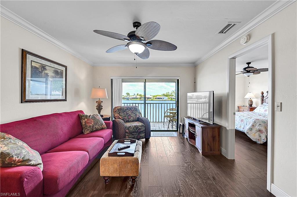 Living area with ceiling fan, wood-style flooring, baseboards, and ornamental molding