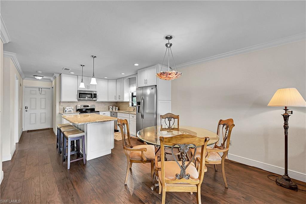 Dining space featuring crown molding, baseboards, dark wood-style floors, and recessed lighting