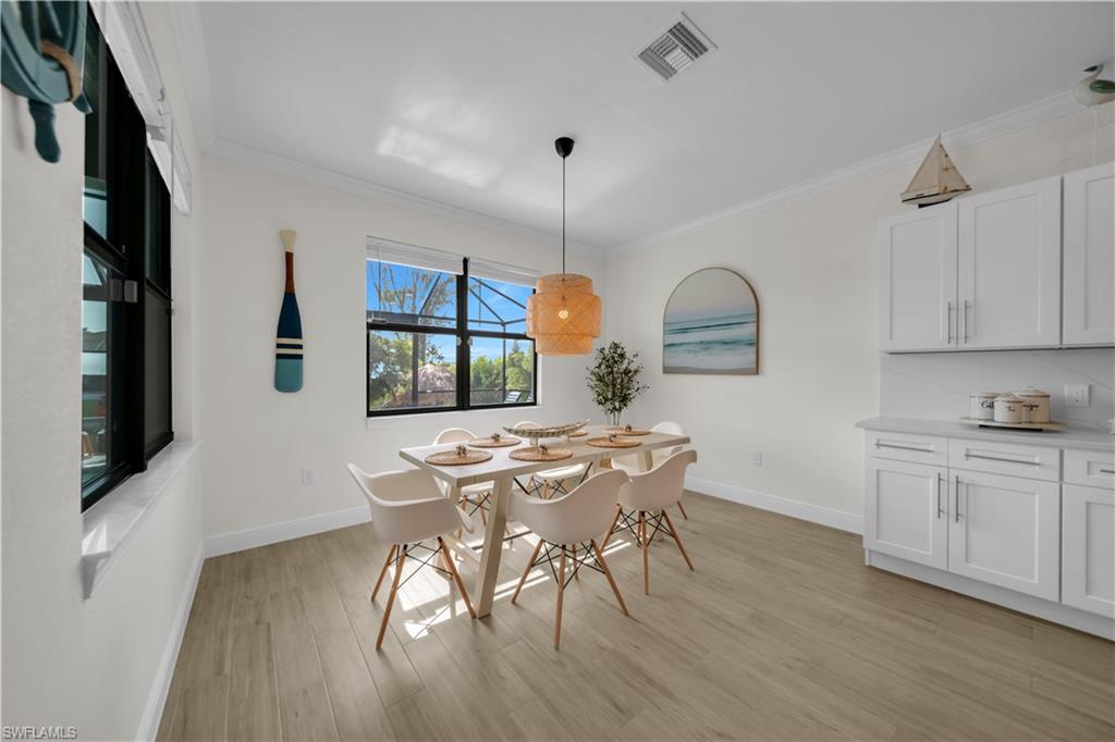 Dining space featuring light wood-style floors, baseboards, and ornamental molding