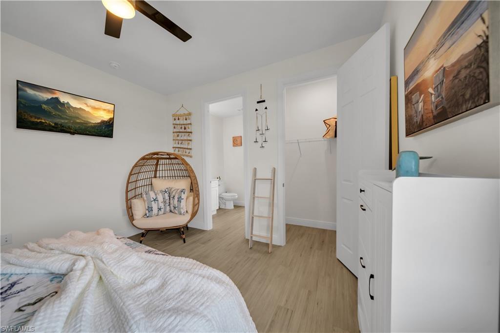 Bedroom featuring light wood-style floors, a walk in closet, a closet, a ceiling fan, and baseboards