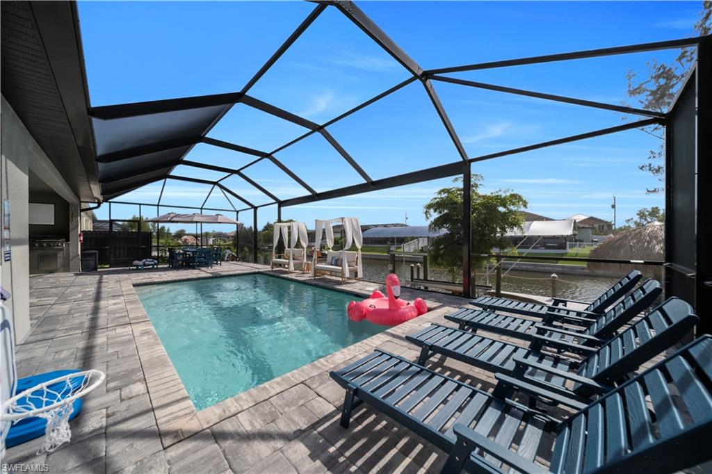 Outdoor pool featuring a patio area, exterior kitchen, and glass enclosure