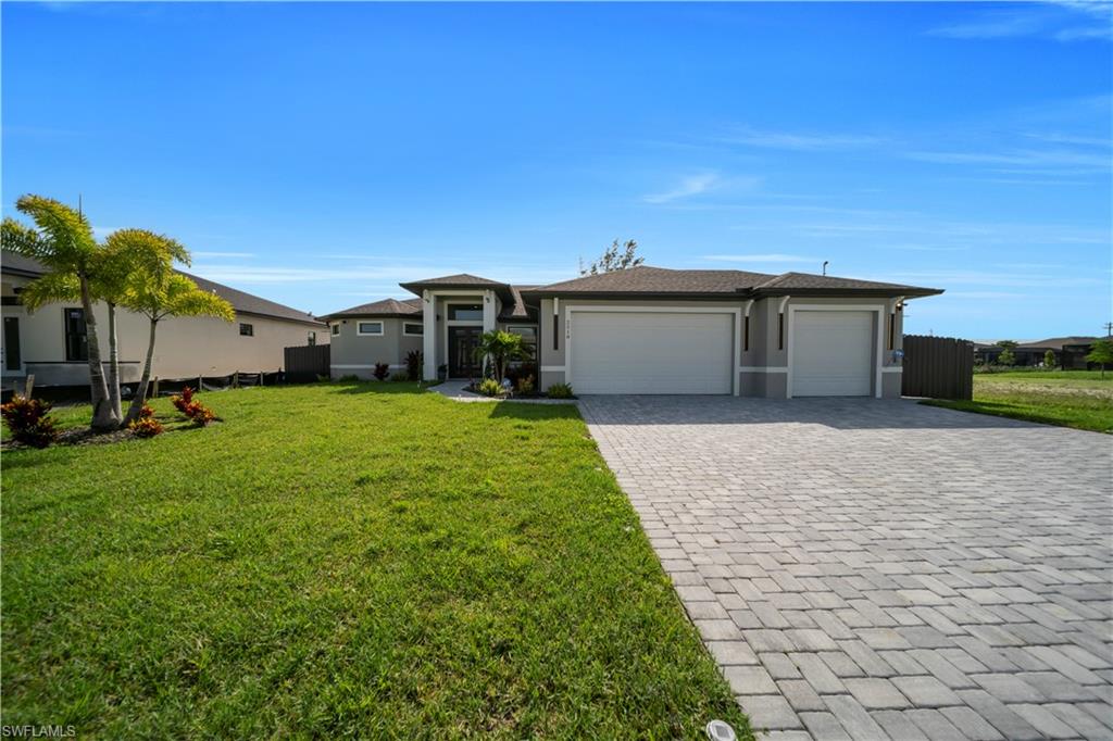View of front of house featuring a garage, decorative driveway, and stucco siding