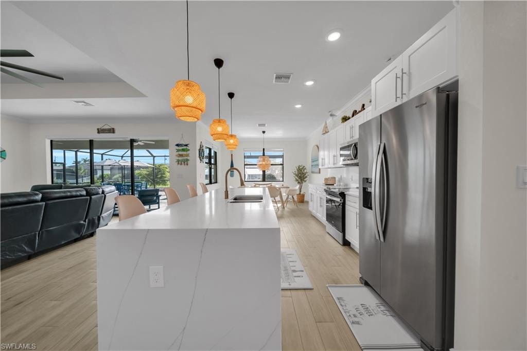 Kitchen with appliances with stainless steel finishes, a sink, ceiling fan, recessed lighting, and a kitchen island with sink