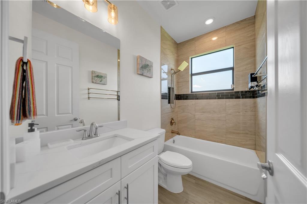 Full bathroom with vanity, toilet,  shower combination, wood finished floors, and recessed lighting