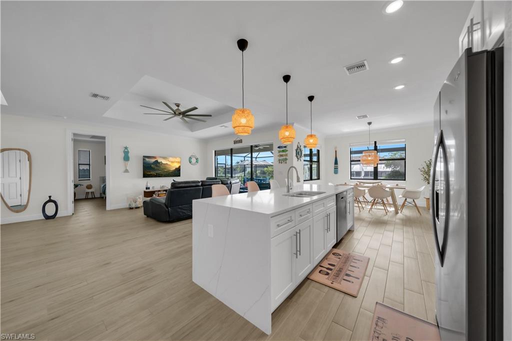 Kitchen with appliances with stainless steel finishes, a sink, light wood-style flooring, recessed lighting, and white cabinets