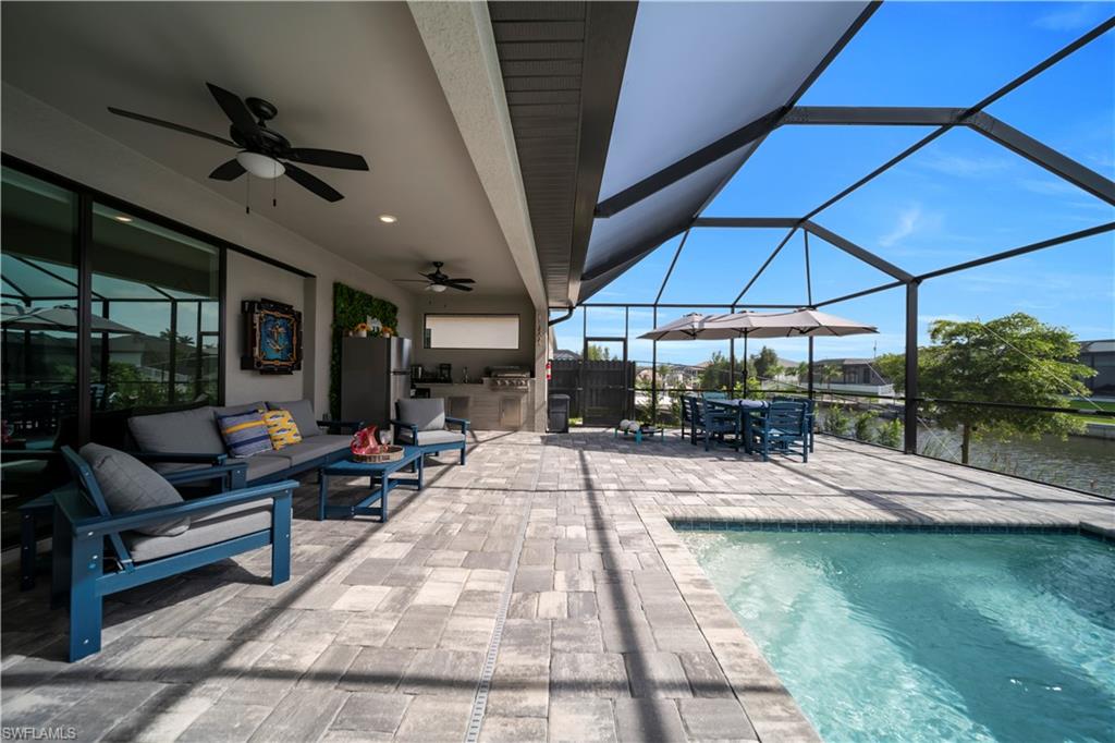 Swimming pool with a patio area, area for grilling, glass enclosure, ceiling fan, and an outdoor living space