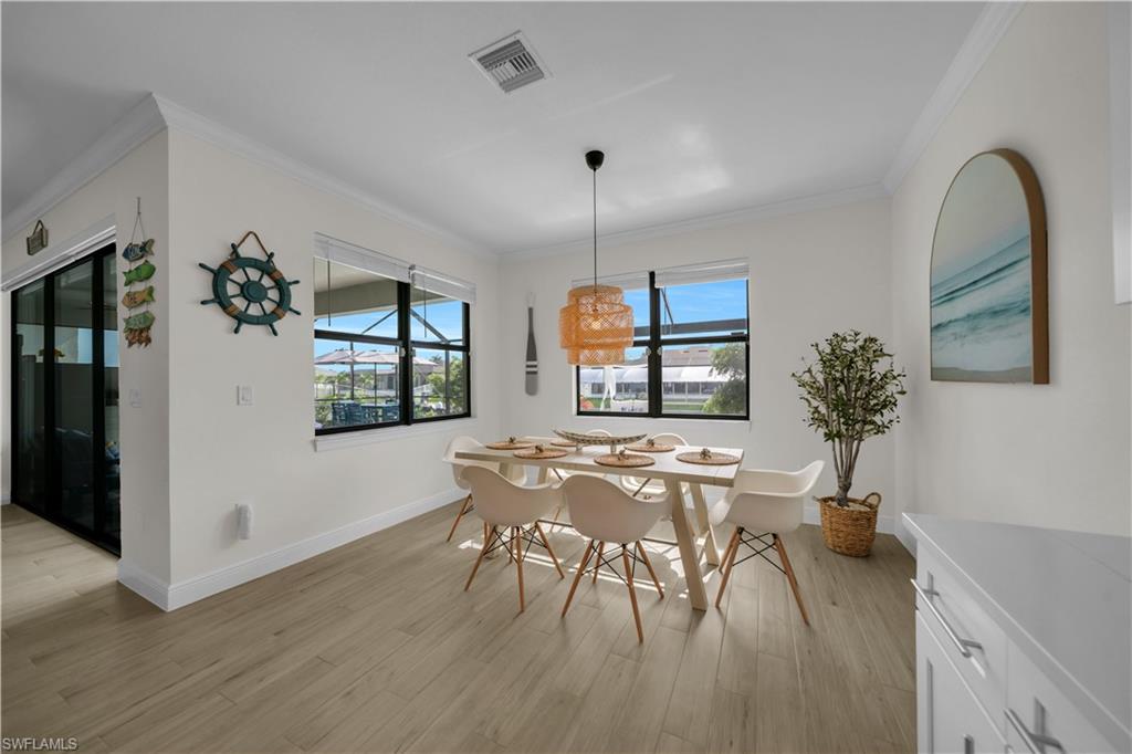 Dining room featuring crown molding, light wood-style floors, and baseboards