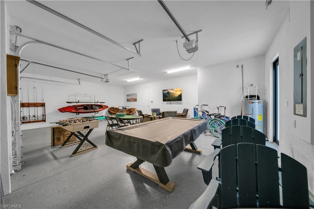 Playroom with water heater, a garage, billiards table, speckle patterned floor, and electric panel