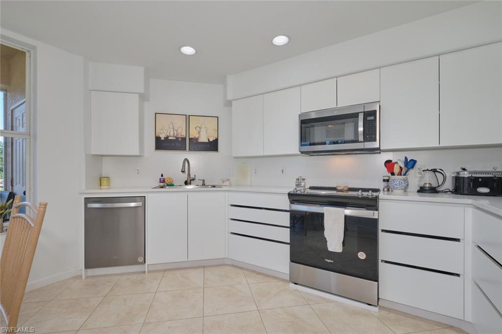 Kitchen with appliances with stainless steel finishes, a sink, light countertops, white cabinetry, and recessed lighting