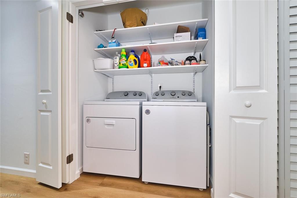Laundry room featuring washer and clothes dryer, light wood-type flooring, and baseboards