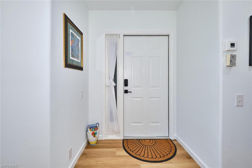 Doorway to outside with light wood finished floors and baseboards