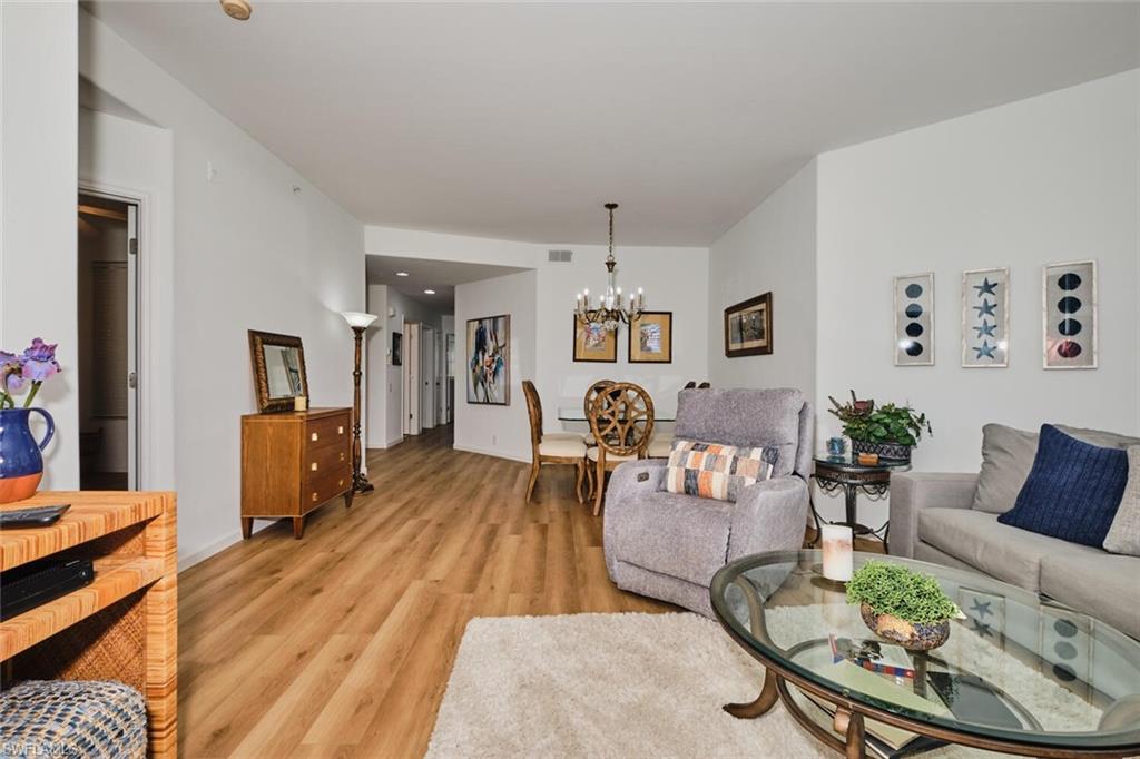 Living room with a chandelier, light wood-style floors, and baseboards