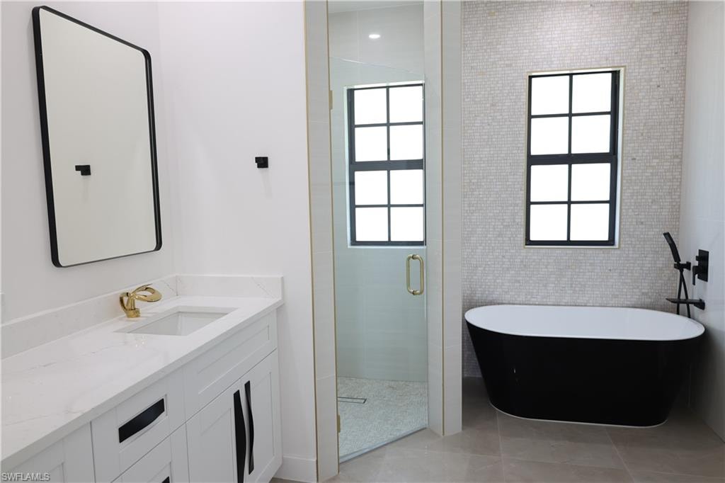 Full bathroom with a freestanding tub, a shower stall, vanity, tile walls, and light tile patterned flooring