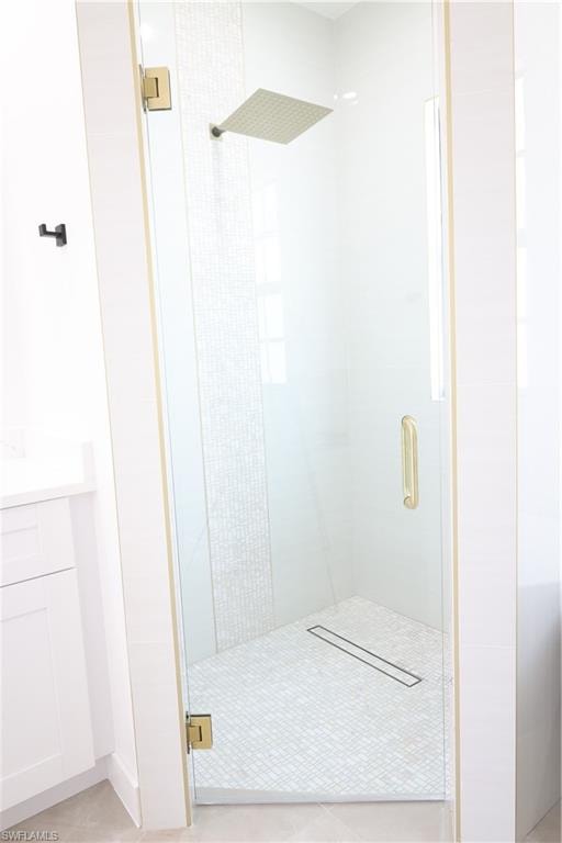 Bathroom featuring vanity, a shower stall, light tile patterned floors, and recessed lighting