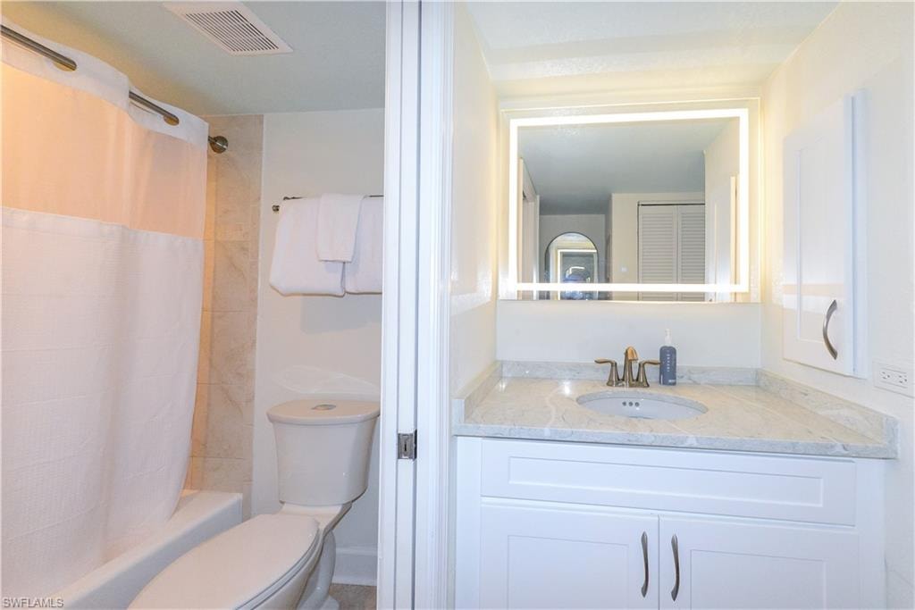Bathroom with toilet, vanity, and shower / bathtub combination with curtain