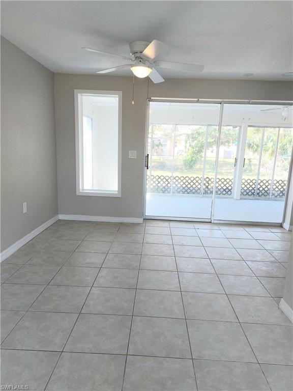 Spare room with a ceiling fan, baseboards, and light tile patterned floors