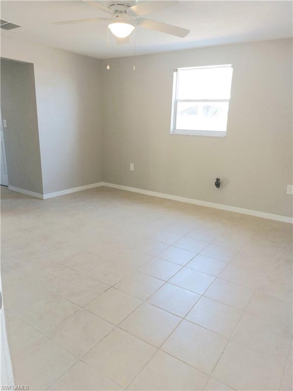 Empty room featuring ceiling fan and baseboards