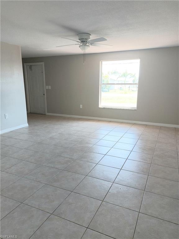 Spare room with a ceiling fan, light tile patterned flooring, and baseboards