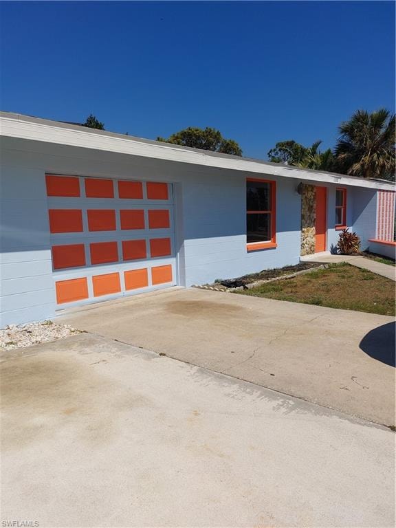 View of front of house with driveway, an attached garage, and concrete block siding