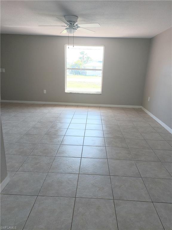 Spare room featuring a ceiling fan, baseboards, and light tile patterned floors