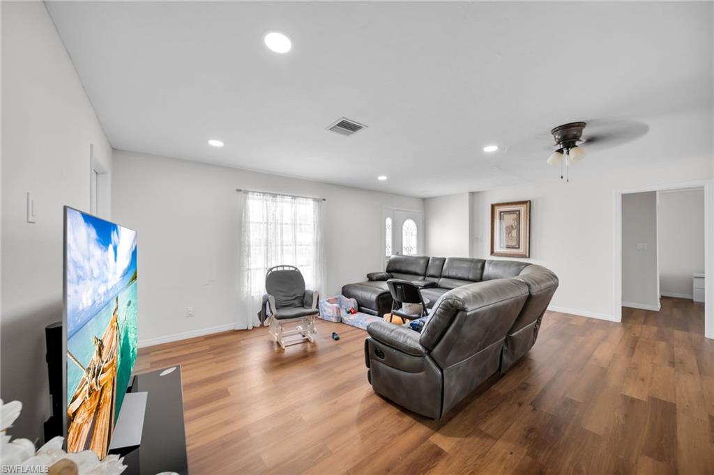 Living room with wood finished floors, recessed lighting, baseboards, and ceiling fan