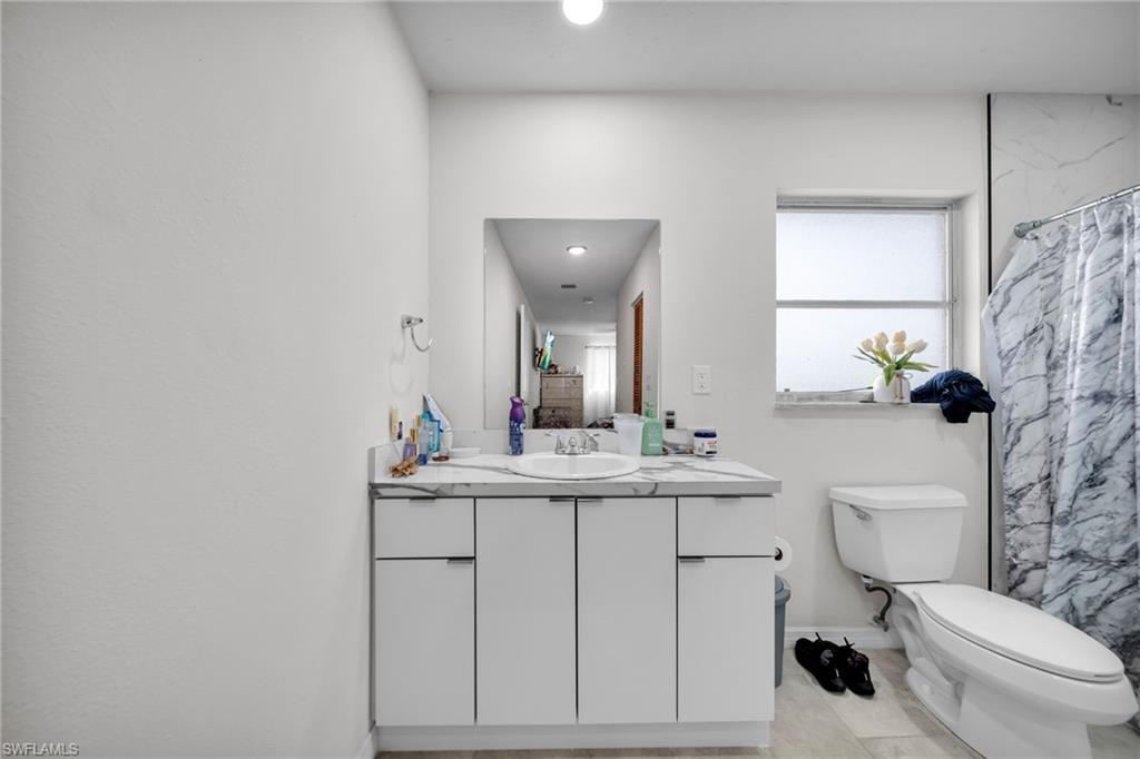 Bathroom featuring vanity, toilet, baseboards, curtained shower, and recessed lighting